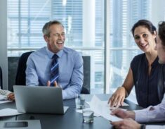 A diverse business team collaborating around a modern conference table with a laptop and papers.