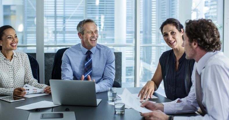 A diverse business team collaborating around a modern conference table with a laptop and papers.