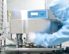 Cleanroom worker beside stainless steel processing equipment and conveyor