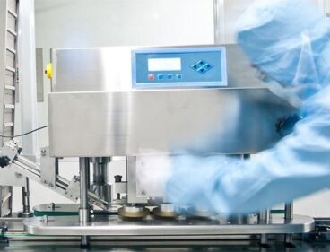 Cleanroom worker beside stainless steel processing equipment and conveyor